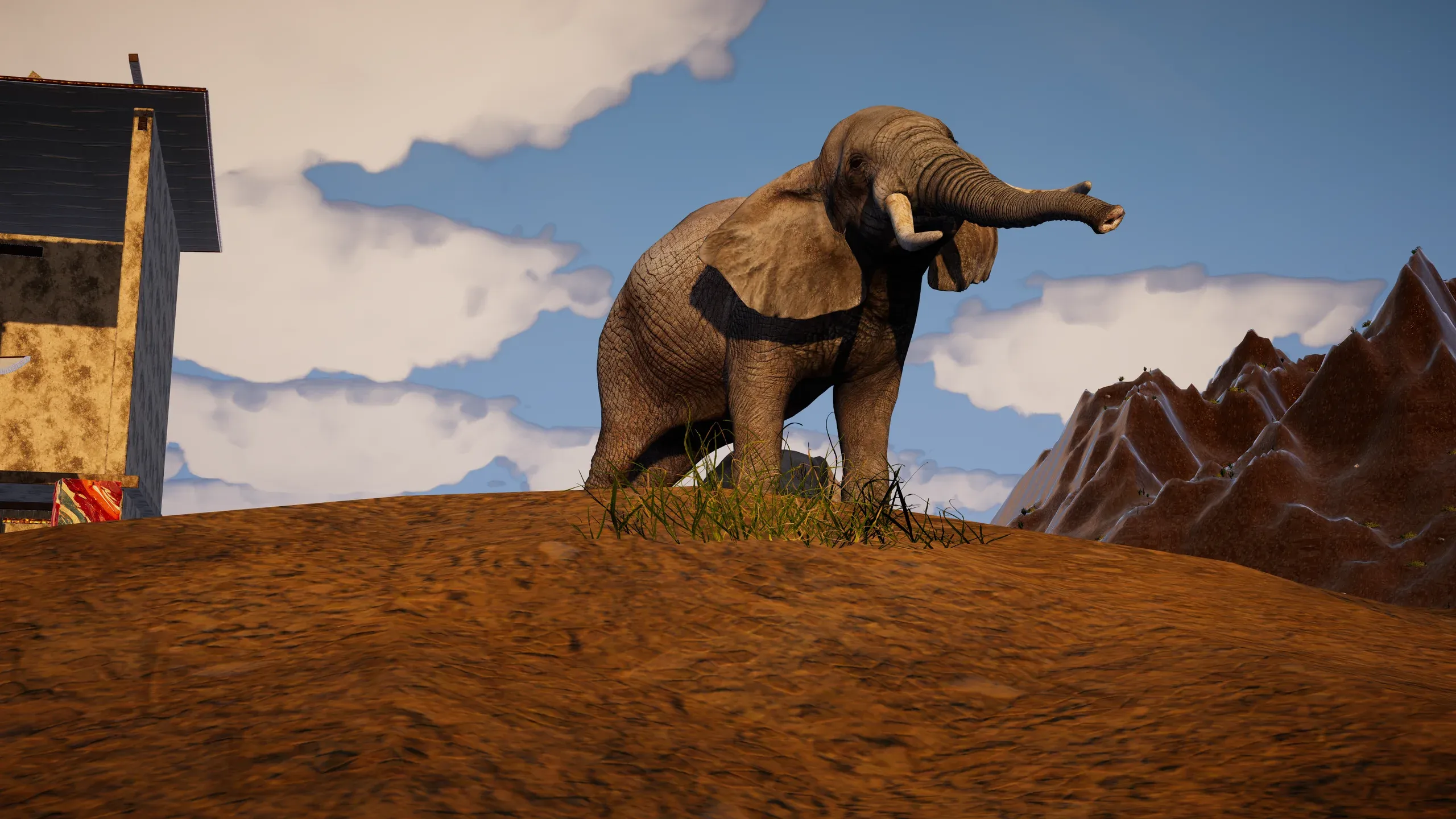 An elephant raising its trunk on a ridge, a timber house and red peaks behind.